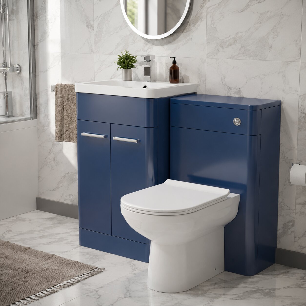 Modern blue toilet and vanity unit combination with integrated basin, white marble-effect wall tiles, round LED mirror and chrome tap in a contemporary UK bathroom.