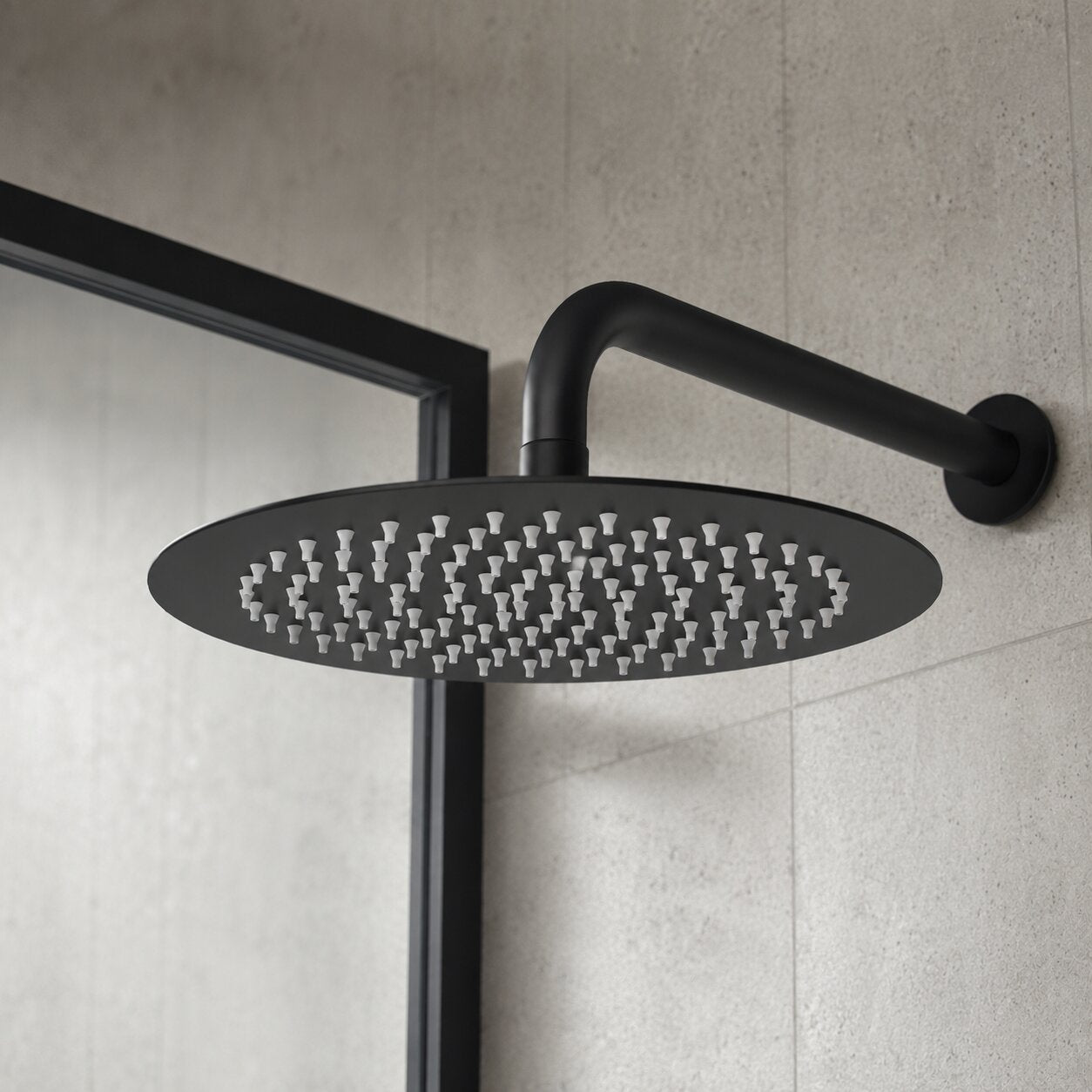 Matte black round rainfall shower head mounted on a modern bathroom wall with a minimalist shower enclosure, creating a luxurious contemporary shower space.