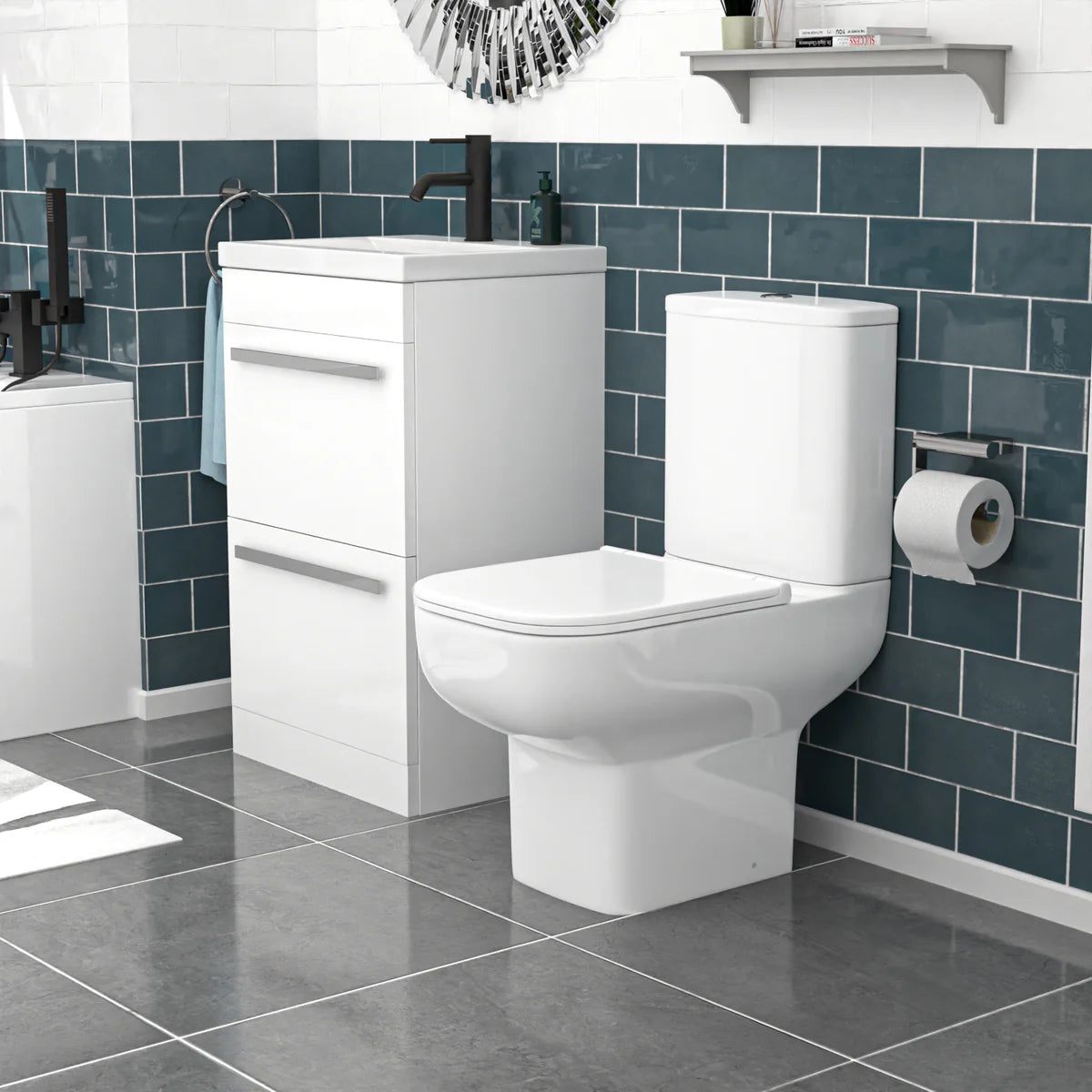 Bathroom setup with white toilet and vanity against a blue tiled wall.
