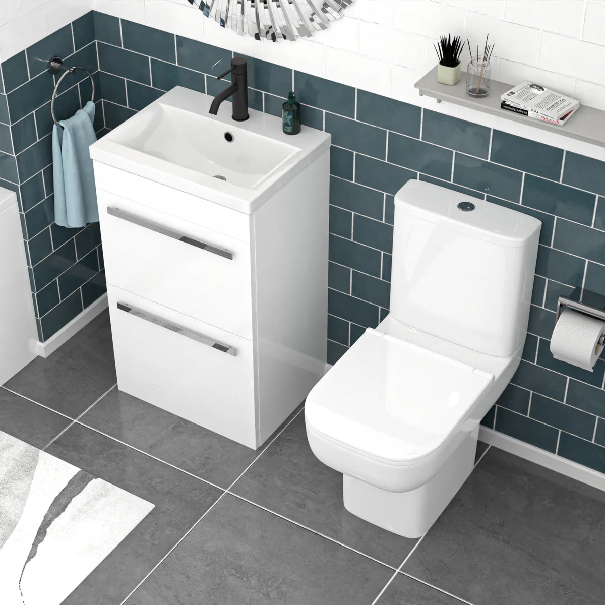 Bathroom setup with white vanity unit, sink, and toilet against a blue tiled wall.