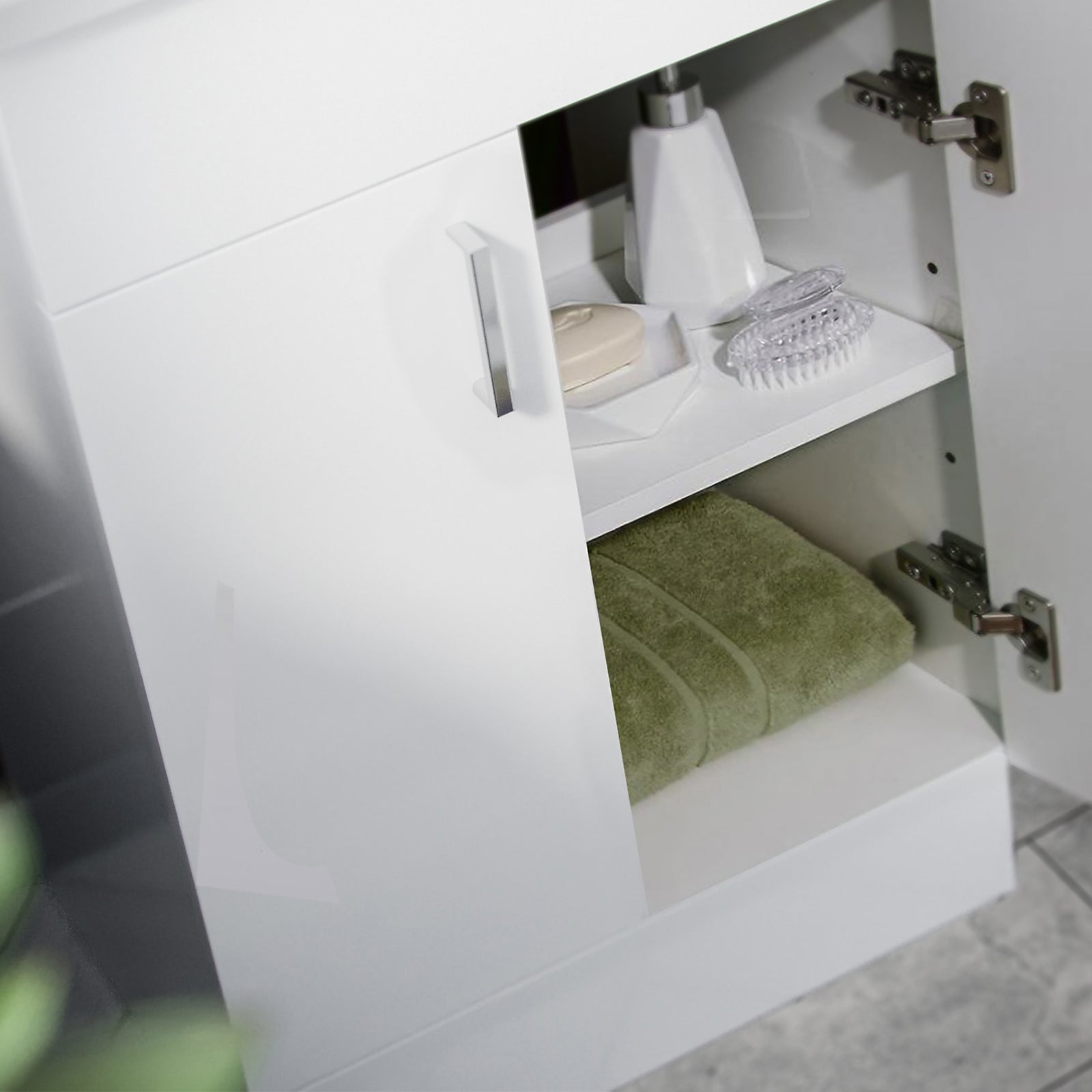 Open white cabinet with green towel and toiletries inside