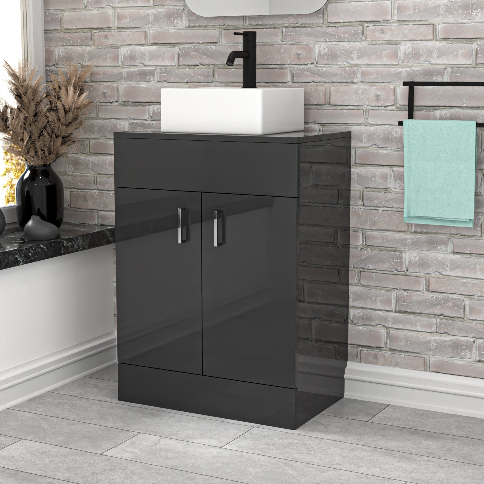 Bathroom vanity with black cabinet and white basin against a brick wall.