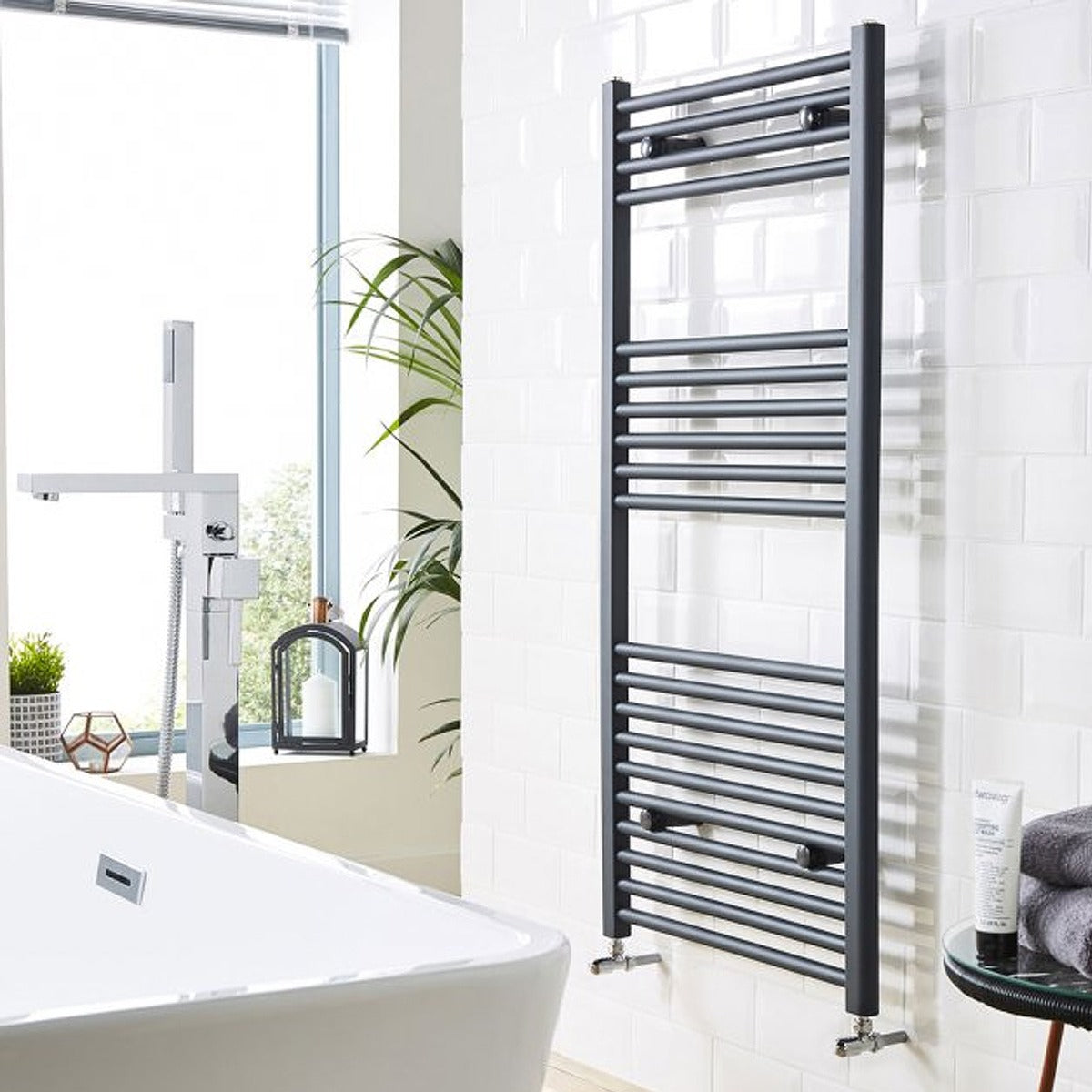 Bathroom with a towel radiator, bathtub, and window