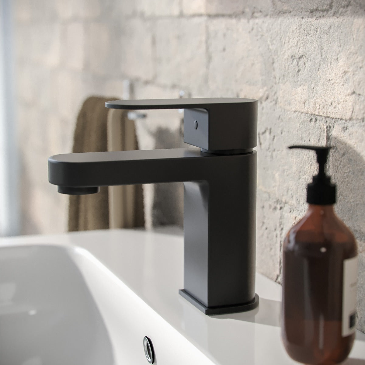 Black faucet on a bathroom sink with a textured wall background