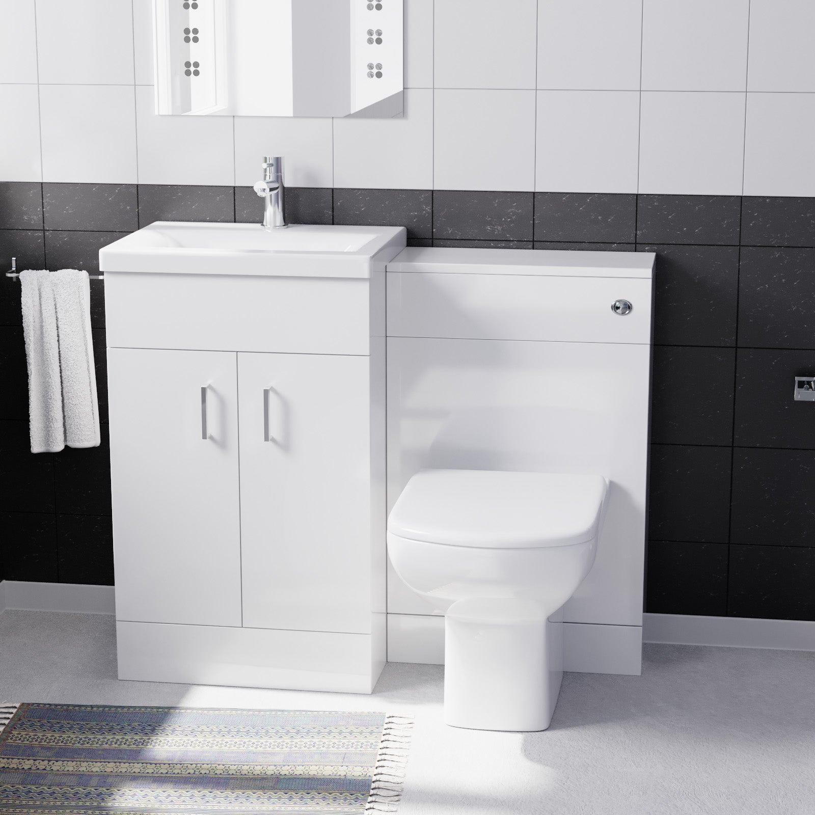 Bathroom setup with white vanity unit, toilet, and mirror in a tiled bathroom.