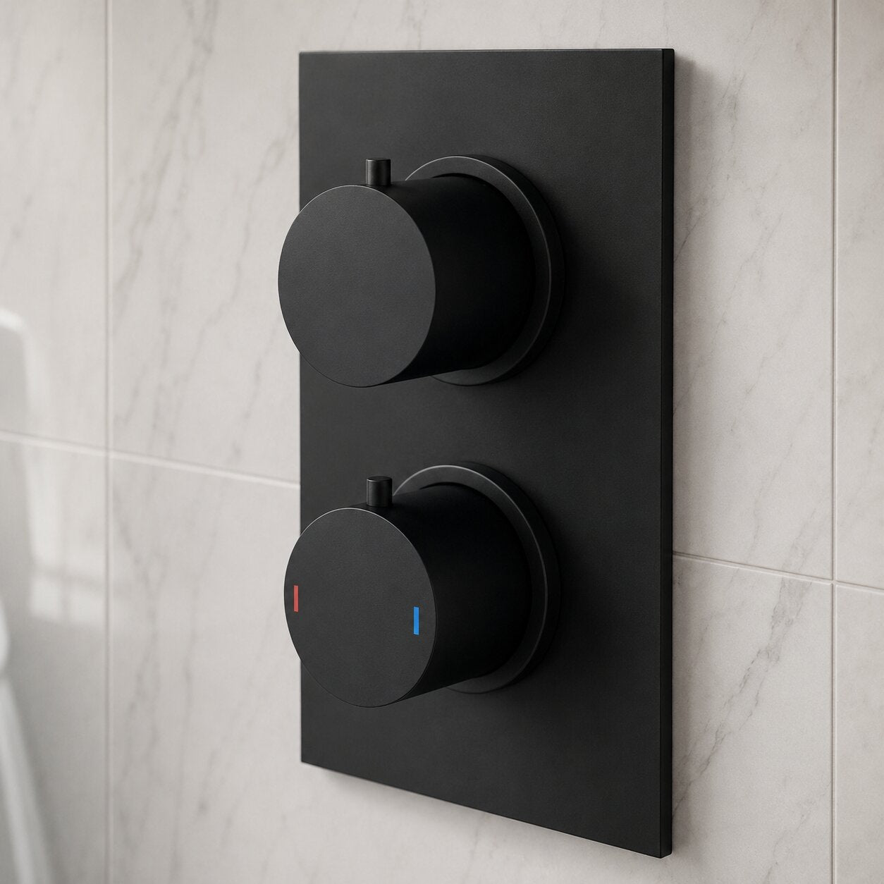Matte black concealed thermostatic shower valve with dual round controls mounted on a rectangular backplate, installed on a marble-effect tiled bathroom wall for a contemporary shower design.