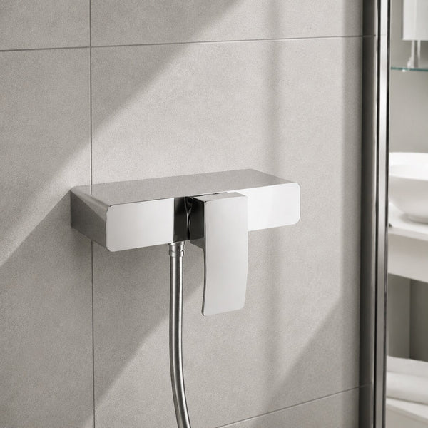 Modern chrome exposed square shower mixer valve with single lever control, polished chrome finish and stone-effect wall tiles in a contemporary UK bathroom.