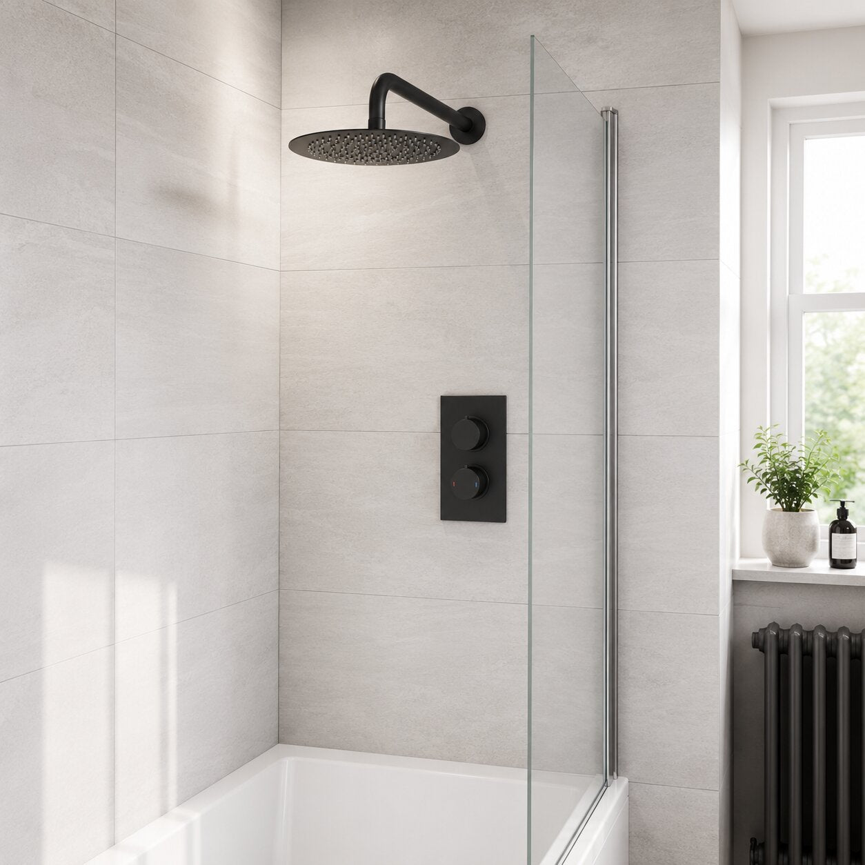 Modern matte black concealed thermostatic rainfall shower with round overhead shower head, concealed dual control valve, glass shower screen, acrylic bath and stone-effect wall tiles in a contemporary UK bathroom.