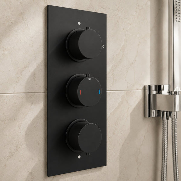 Modern matte black concealed thermostatic triple shower valve with precision temperature control, three-function diverter controls and stone-effect wall tiles in a contemporary UK bathroom.