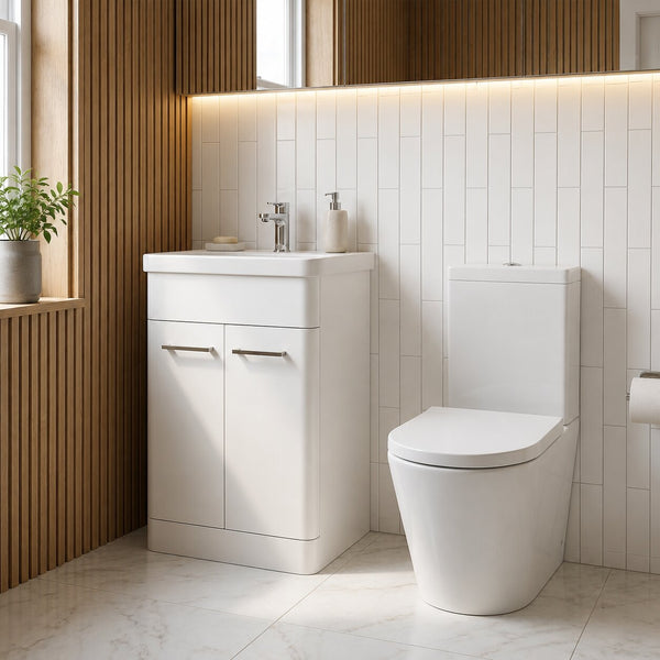 Modern white toilet and vanity unit with integrated ceramic basin, timber slat feature wall, white vertical wall tiles, LED mirror lighting and marble-effect floor tiles in a contemporary UK bathroom.