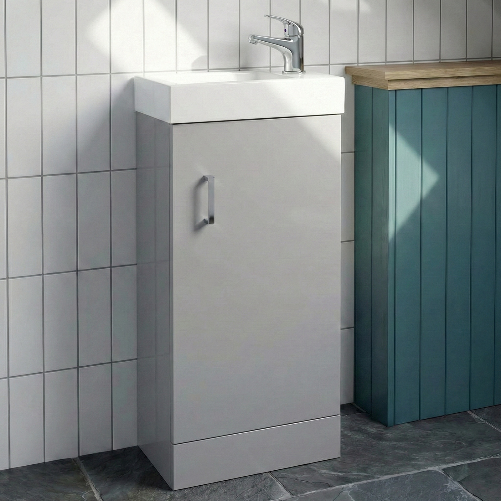 Bathroom setup with a gray vanity unit, white sink, and teal cabinet.