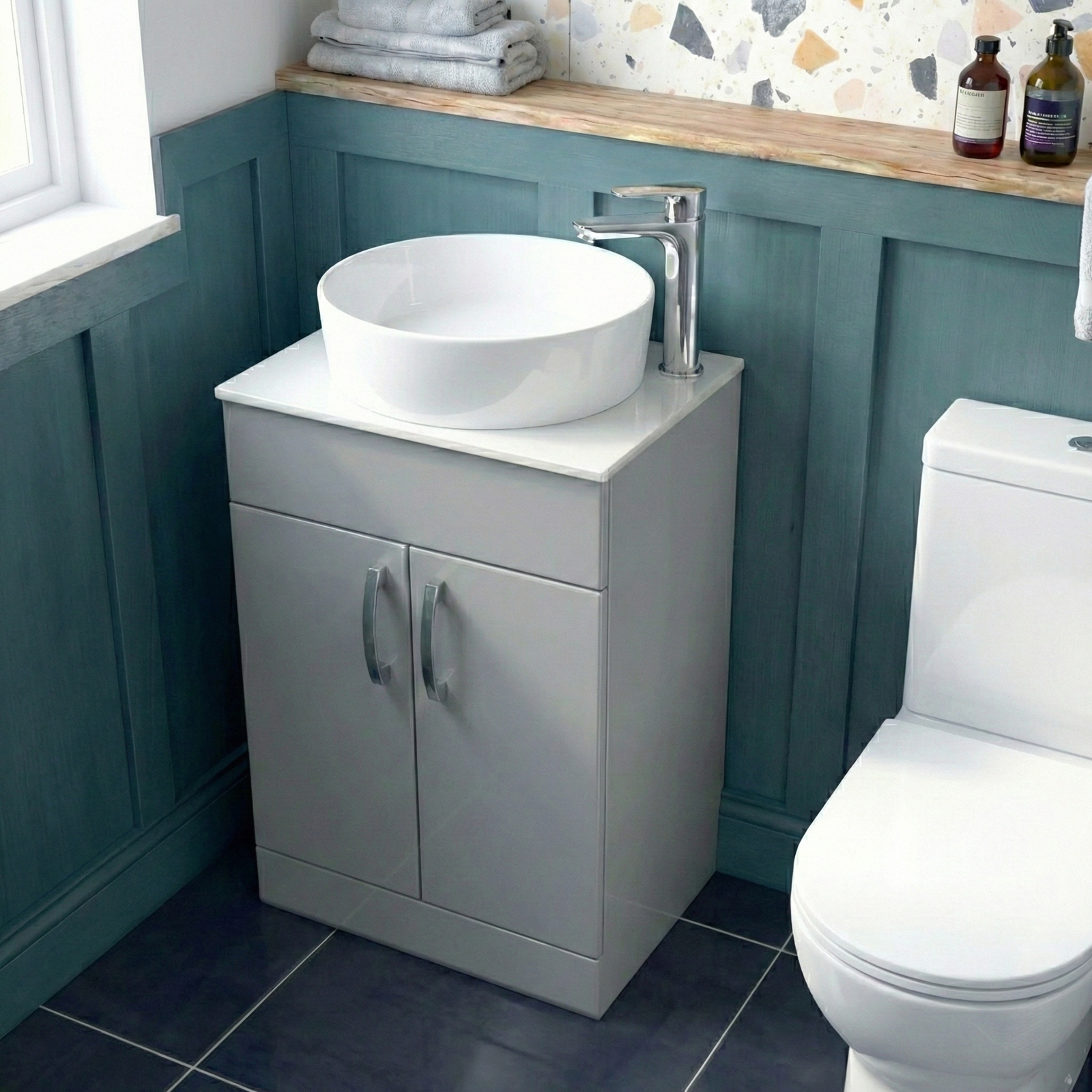 Bathroom with a white sink on a gray cabinet, toilet, and teal walls.