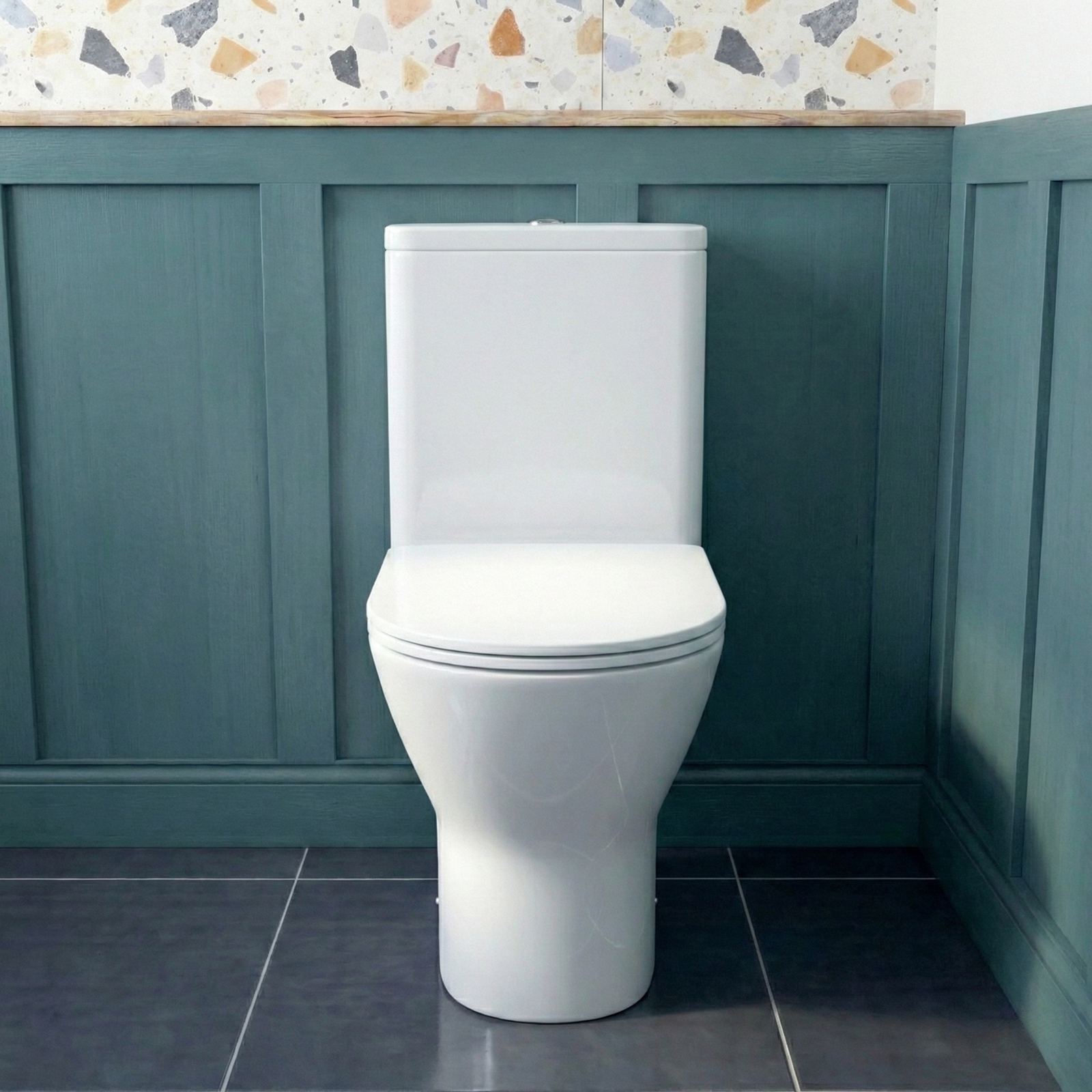 White toilet in a bathroom with green paneling and a patterned tile.