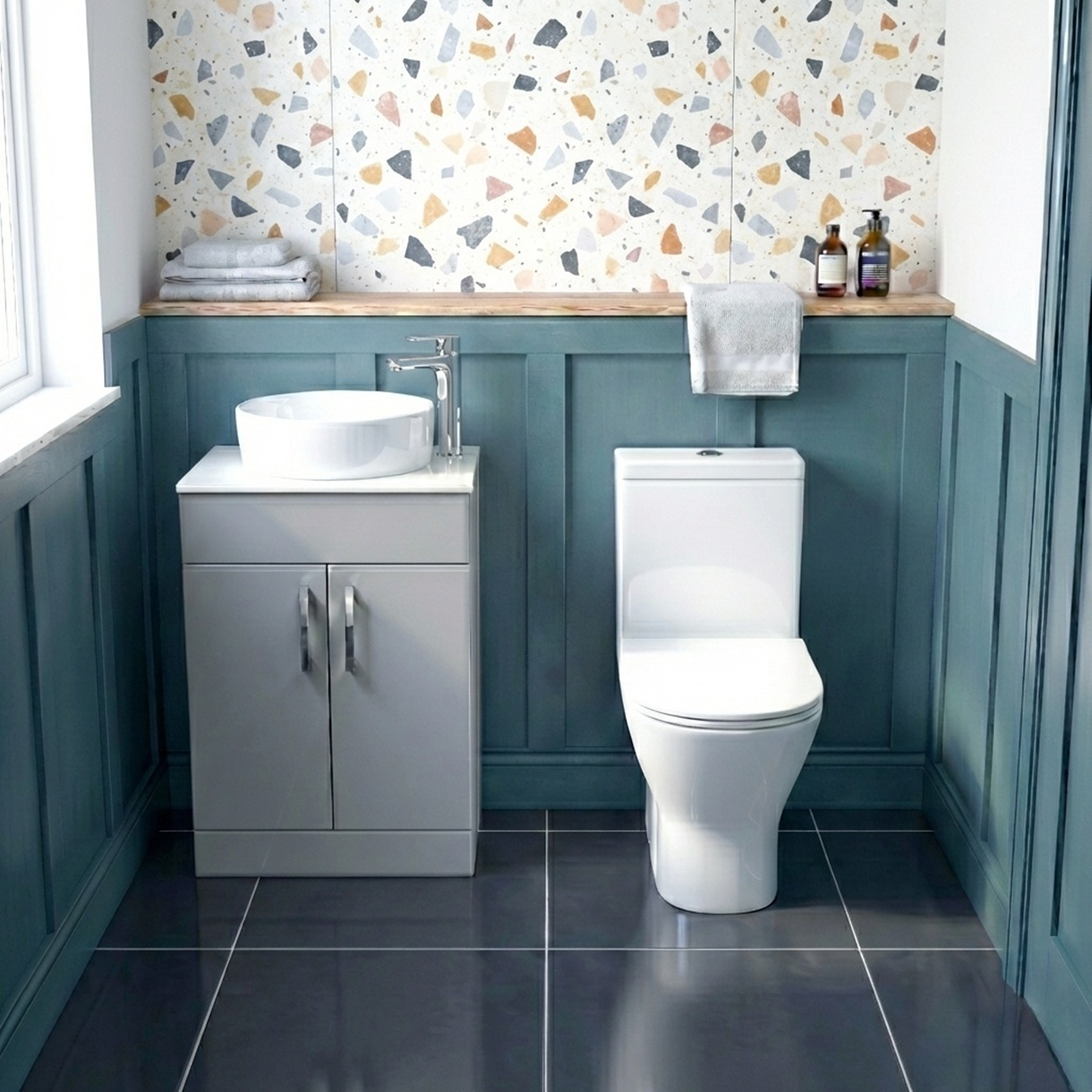 Modern bathroom with teal walls, white toilet, sink, and decorative wallpaper.