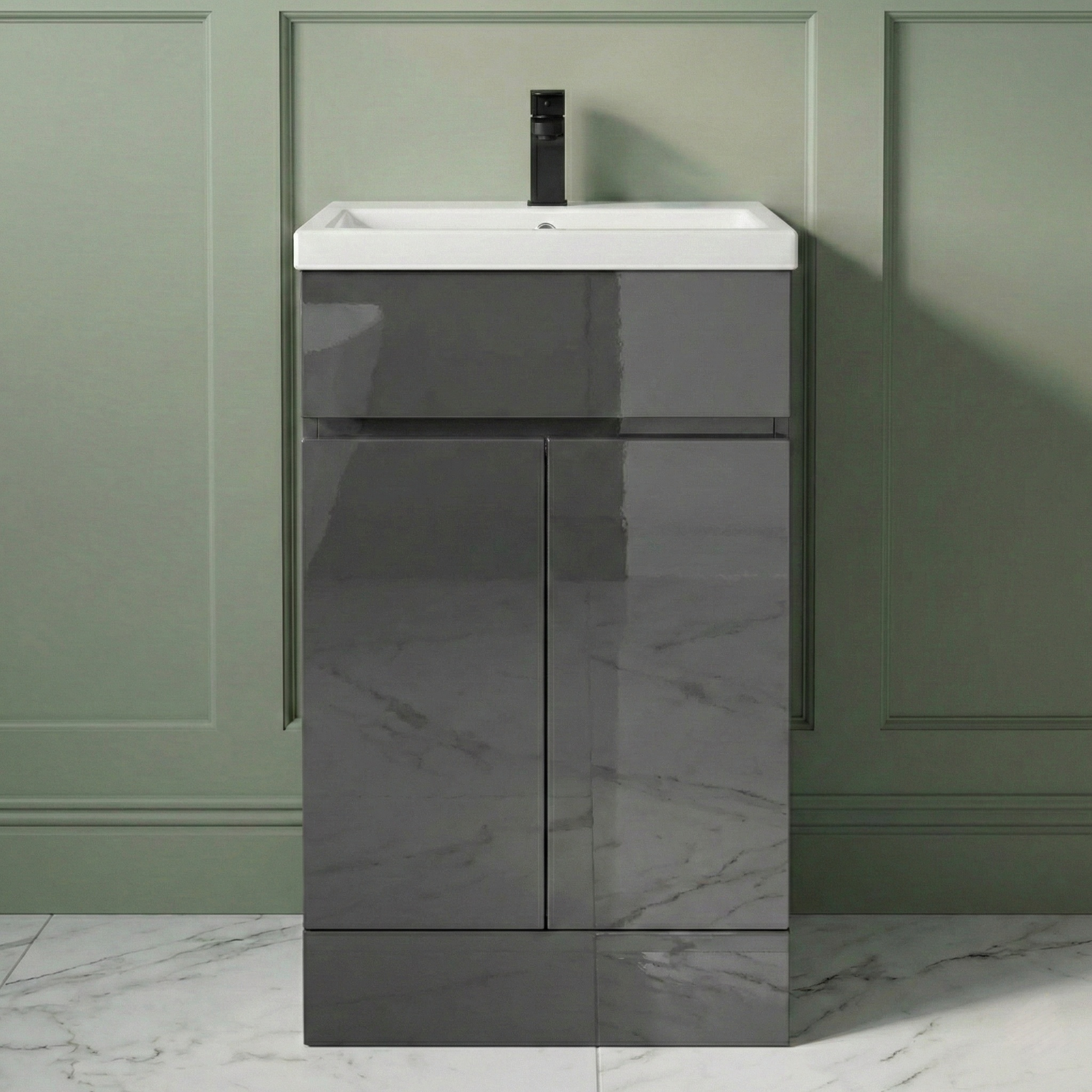 Bathroom vanity with white sink and dark gray cabinet against a green wall.