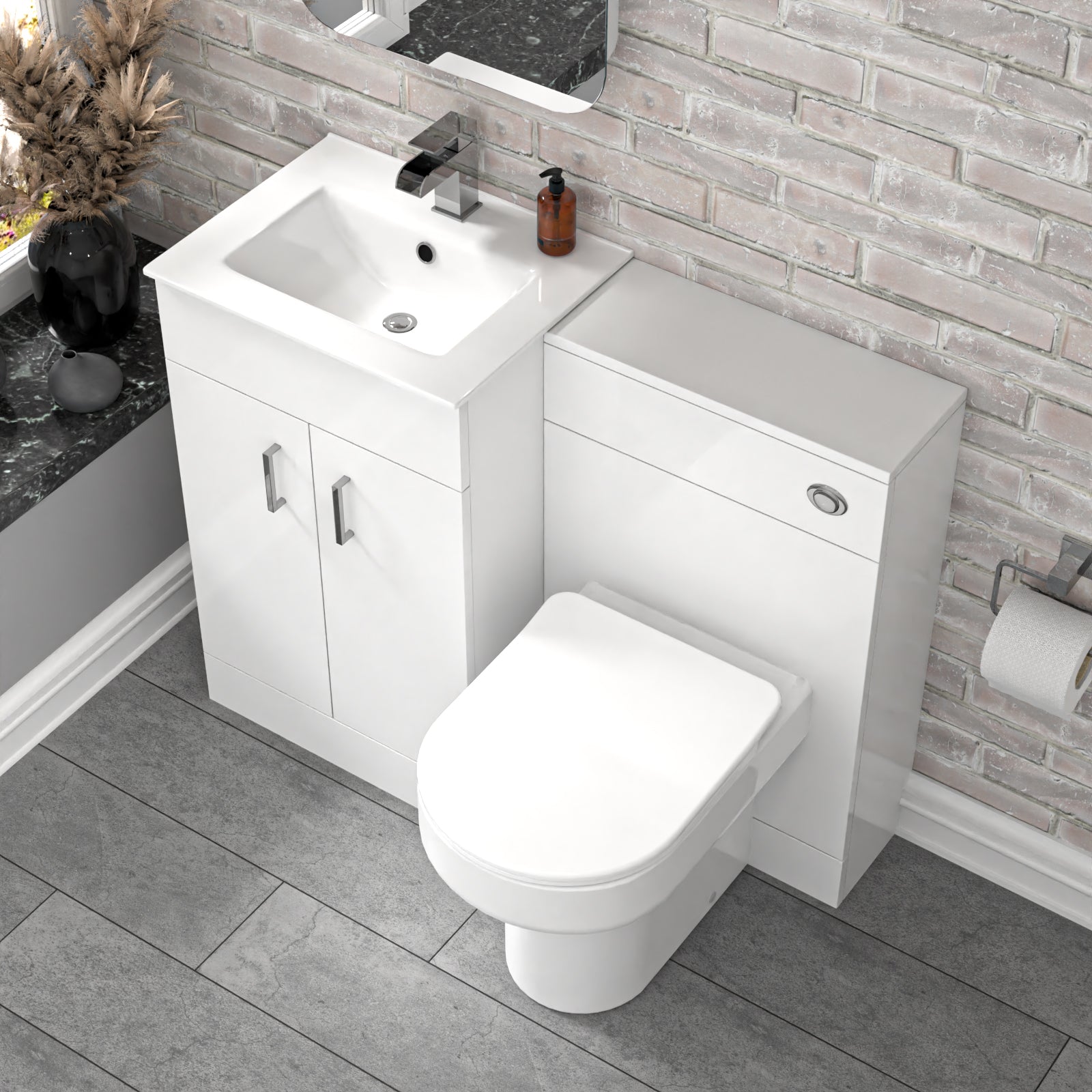 Bathroom setup with white vanity unit, sink, and toilet and faucet against a tiled wall.