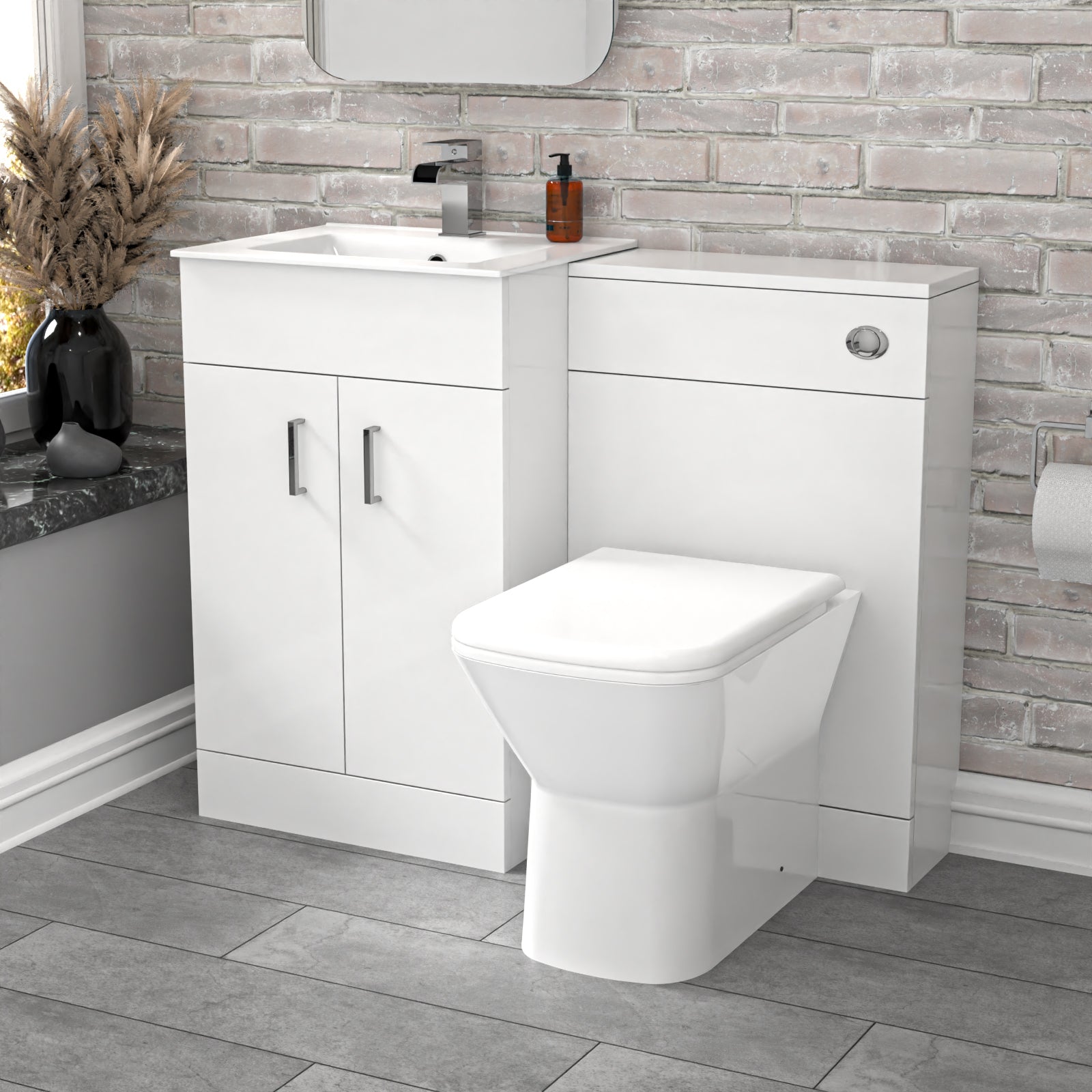 Bathroom setup with white vanity unit, sink, and toilet against a brick-patterned wall.