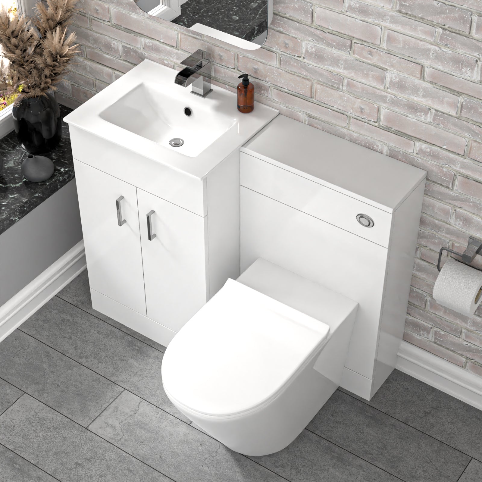 Bathroom setup with white vanity unit, sink, and toilet against a brick wall.