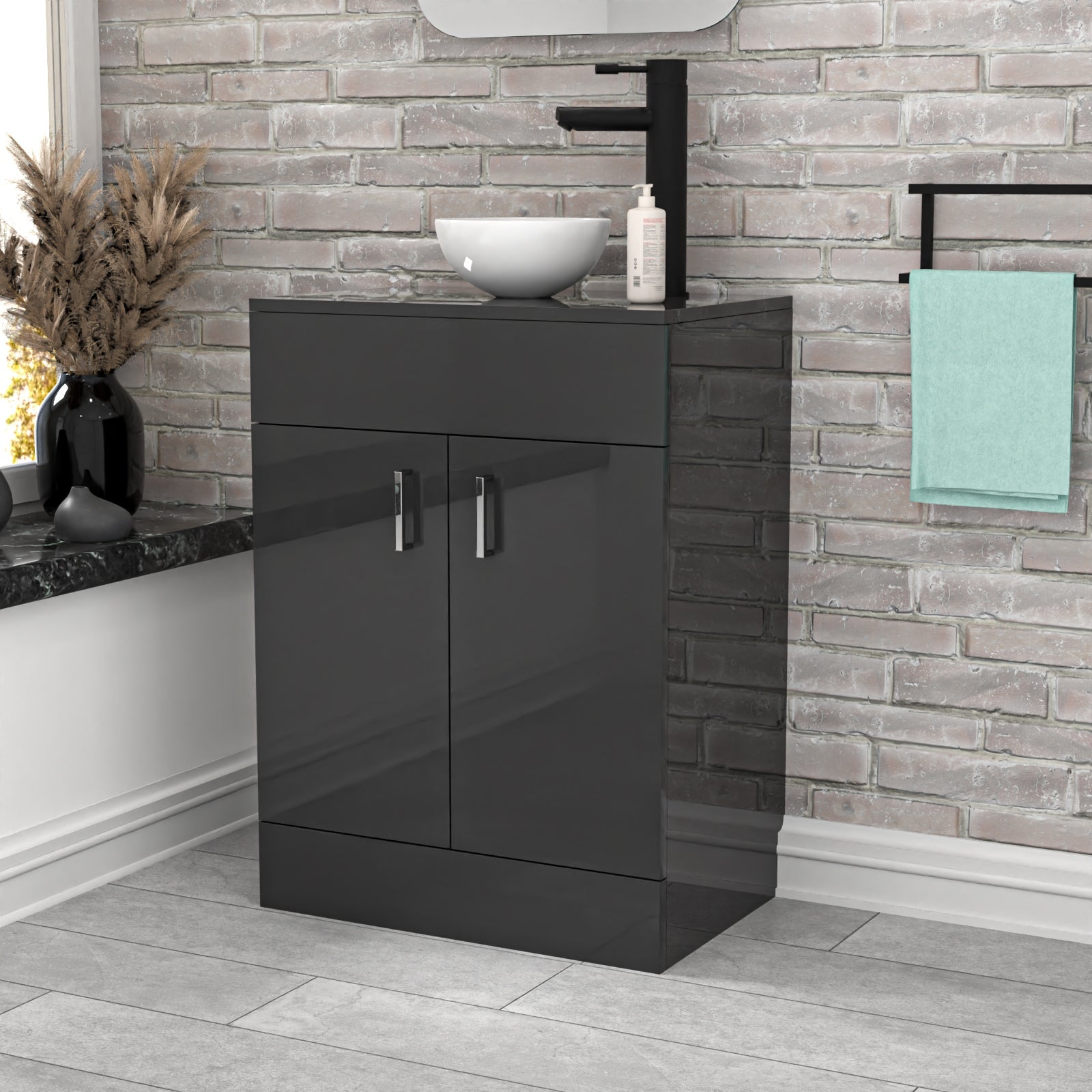 Bathroom vanity with black cabinet, sink, and towel against a brick wall.