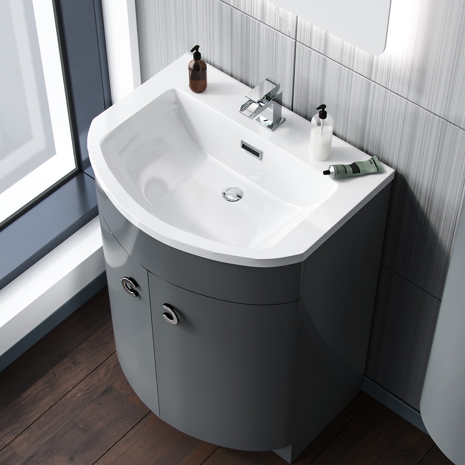 Bathroom vanity with white sink and gray cabinet against a tiled wall.