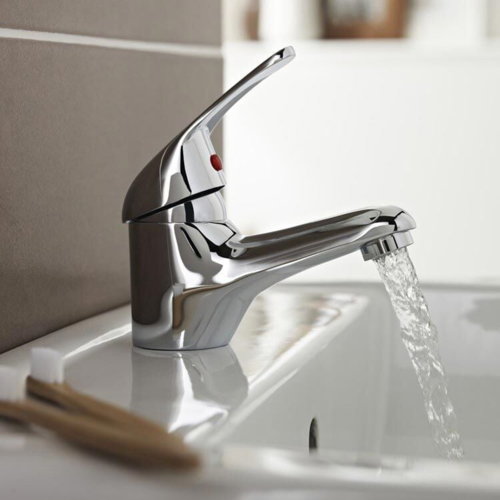 Chrome faucet with water flowing into a sink in a bathroom setting