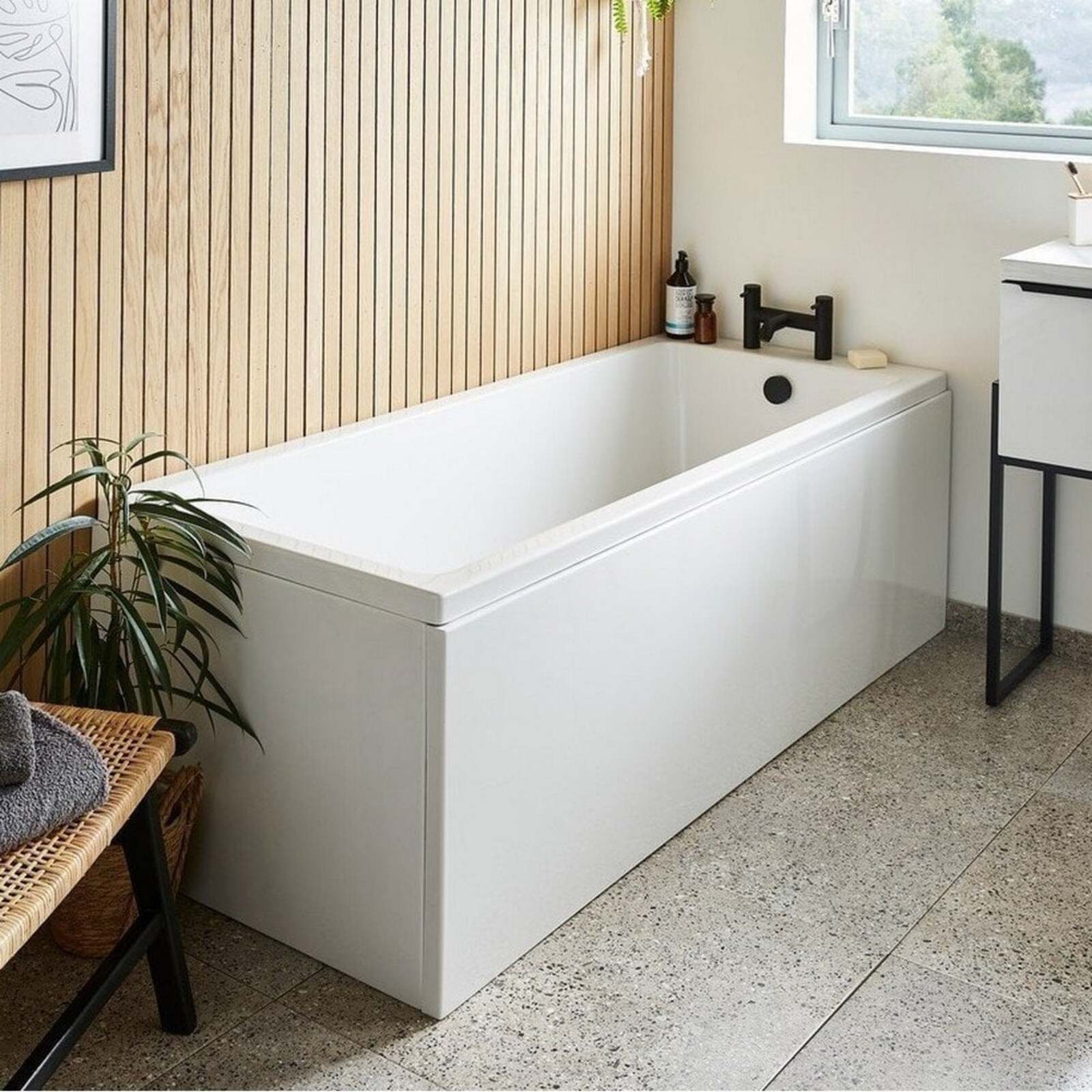 Modern bathroom with a white bathtub, plant, and window.