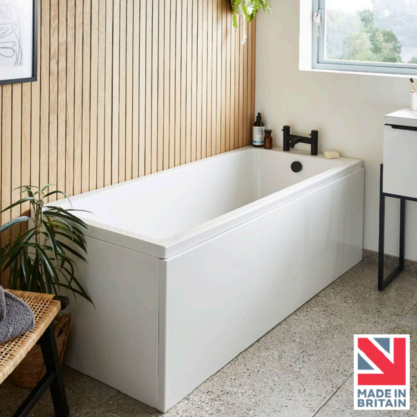 White freestanding bathtub in a modern bathroom with a 'Made in Britain' badge.