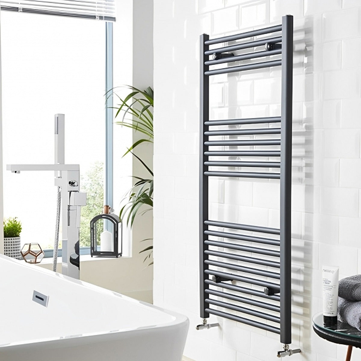 Towel radiator in a bathroom setting with a bathtub and window.