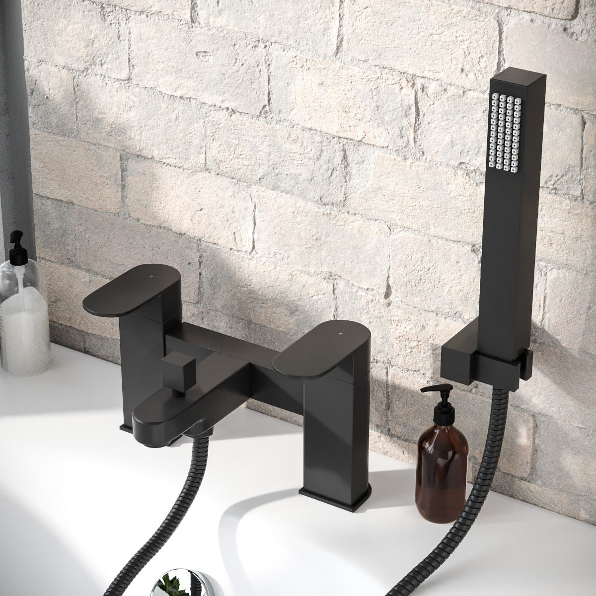 Black bathtub faucet and shower head against a stone wall.